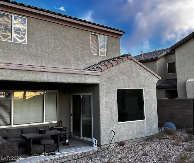 back of property with an outdoor living space and a patio