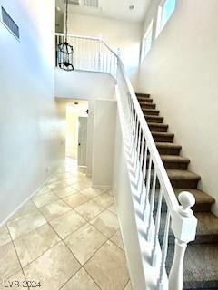 stairs featuring tile patterned floors and an inviting chandelier