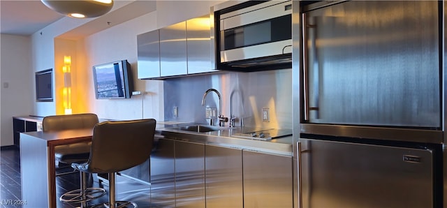 kitchen with appliances with stainless steel finishes, hardwood / wood-style flooring, sink, and stainless steel counters