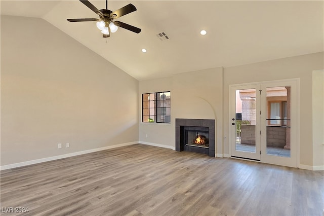 unfurnished living room featuring ceiling fan, a healthy amount of sunlight, a tiled fireplace, and light wood-type flooring