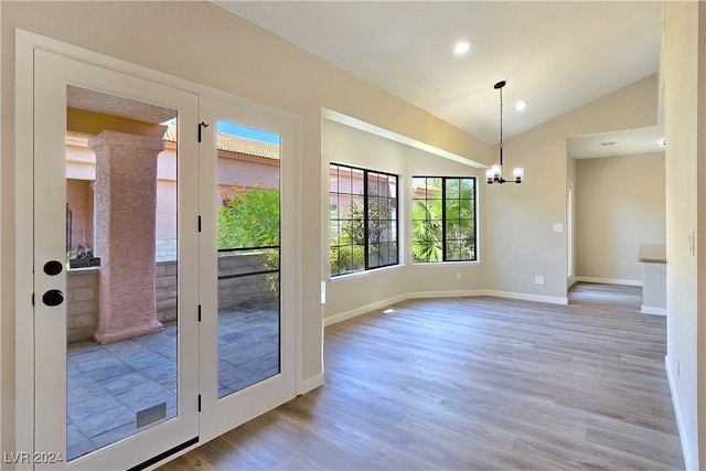 doorway featuring lofted ceiling, light hardwood / wood-style flooring, and a chandelier