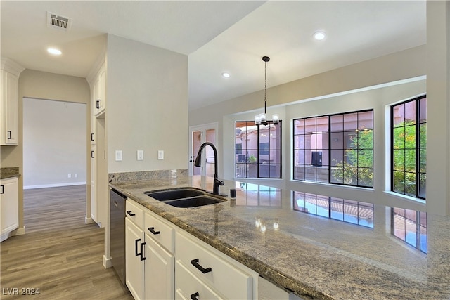 kitchen with sink, light hardwood / wood-style flooring, dark stone countertops, hanging light fixtures, and white cabinets