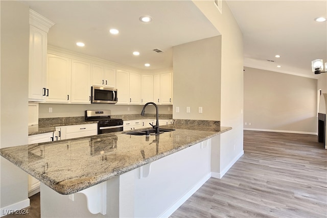 kitchen featuring white cabinetry, gas range, sink, and kitchen peninsula