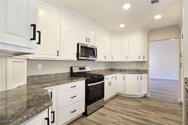 kitchen featuring stainless steel appliances, white cabinetry, light hardwood / wood-style flooring, and dark stone counters