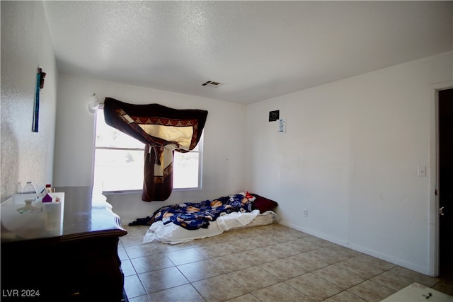 bedroom featuring light tile patterned floors and a textured ceiling