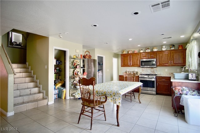 kitchen with appliances with stainless steel finishes, light tile patterned floors, and tasteful backsplash