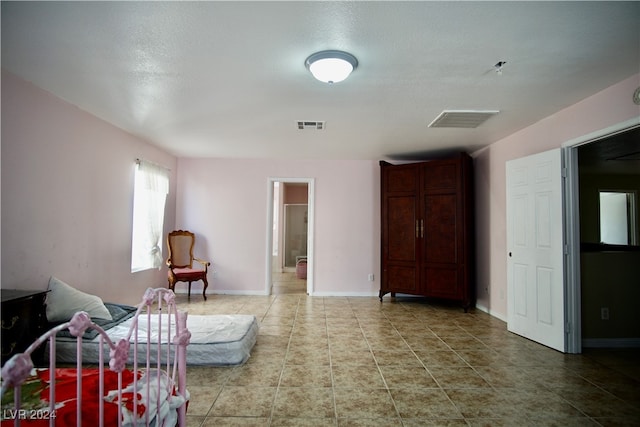 bedroom featuring ensuite bathroom, tile patterned flooring, and a textured ceiling