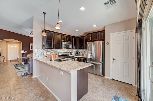 kitchen featuring kitchen peninsula, stainless steel appliances, sink, light stone countertops, and decorative light fixtures