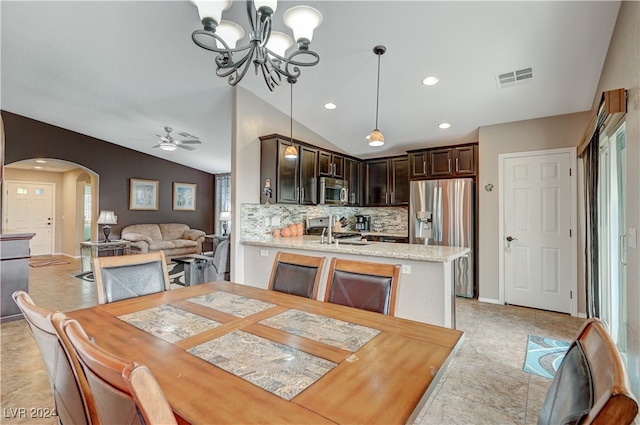 dining space with sink, vaulted ceiling, a wealth of natural light, and ceiling fan with notable chandelier