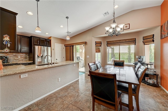 dining space with a notable chandelier, sink, light tile patterned floors, and vaulted ceiling