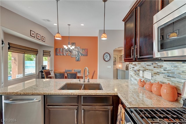 kitchen featuring sink, hanging light fixtures, stainless steel appliances, decorative backsplash, and an inviting chandelier