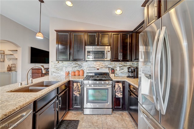 kitchen featuring lofted ceiling, sink, dark brown cabinetry, decorative light fixtures, and appliances with stainless steel finishes