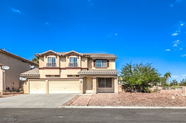 mediterranean / spanish house with driveway, an attached garage, a tile roof, and stucco siding