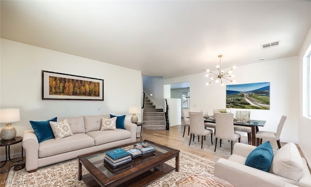 living area with an inviting chandelier, stairs, visible vents, and light wood-style floors