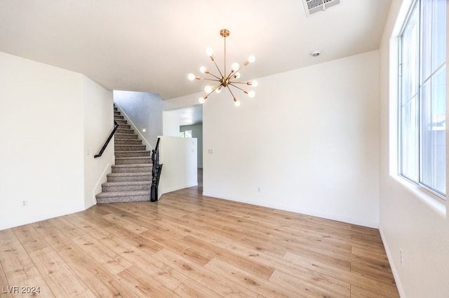 spare room featuring a wealth of natural light, stairway, light wood-style flooring, and visible vents