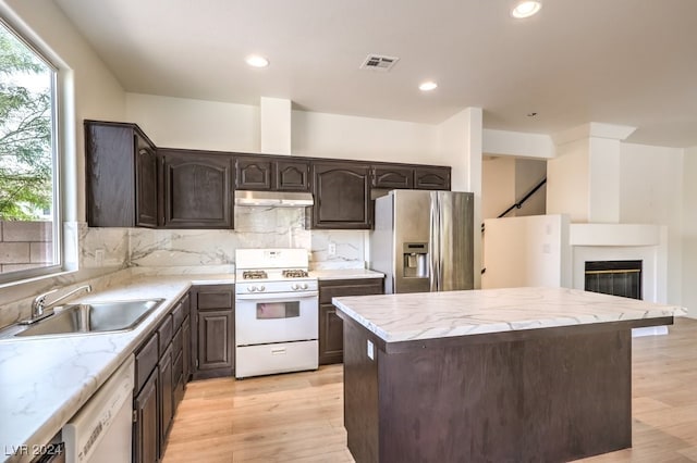 kitchen featuring dark brown cabinetry, white appliances, visible vents, under cabinet range hood, and a sink