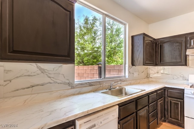 kitchen with dark brown cabinets, white appliances, a sink, and decorative backsplash