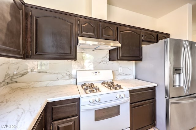 kitchen featuring under cabinet range hood, dark brown cabinets, stainless steel fridge with ice dispenser, tasteful backsplash, and gas range gas stove