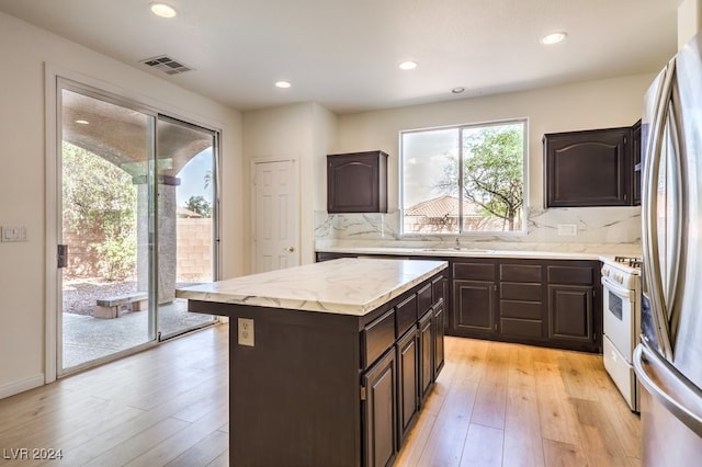 kitchen with light wood-style floors, visible vents, backsplash, and gas range gas stove