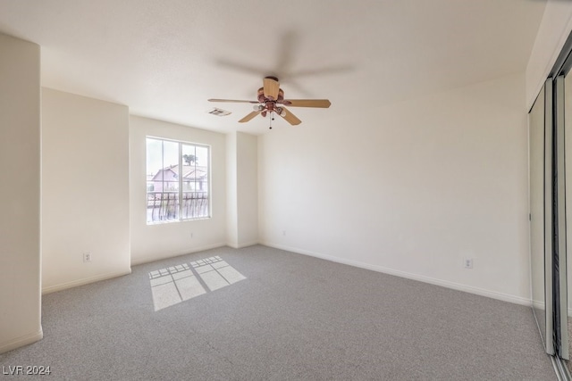 carpeted empty room with visible vents, ceiling fan, and baseboards