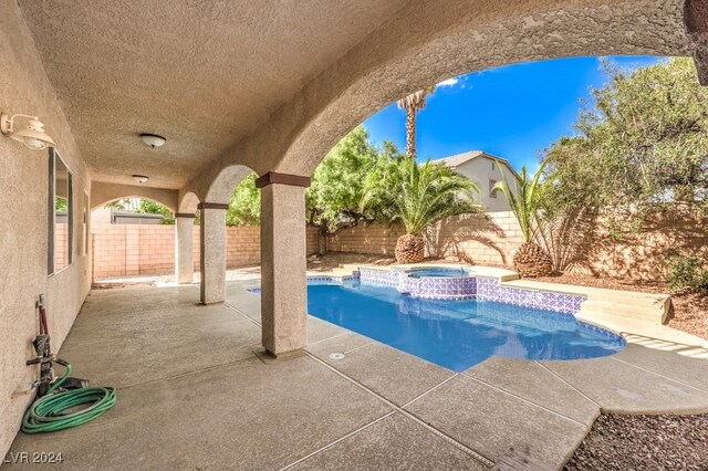 view of swimming pool featuring a fenced backyard, a pool with connected hot tub, and a patio