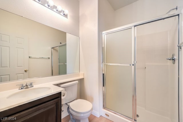 bathroom featuring toilet, a shower stall, baseboards, and vanity