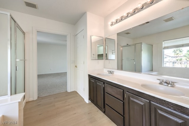 full bathroom featuring visible vents, a sink, a shower stall, and double vanity