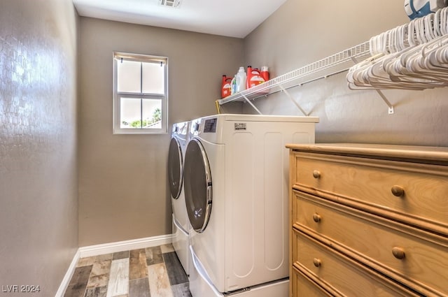 laundry room with washing machine and clothes dryer and hardwood / wood-style flooring