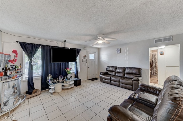 living room featuring a textured ceiling, light tile patterned floors, and ceiling fan