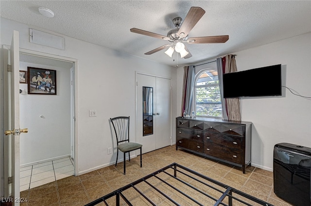 bedroom with heating unit, light tile patterned floors, ceiling fan, a textured ceiling, and a closet