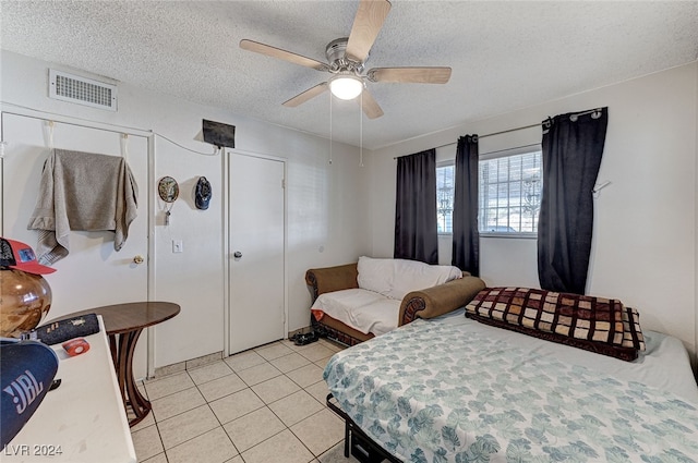 tiled bedroom with a textured ceiling and ceiling fan