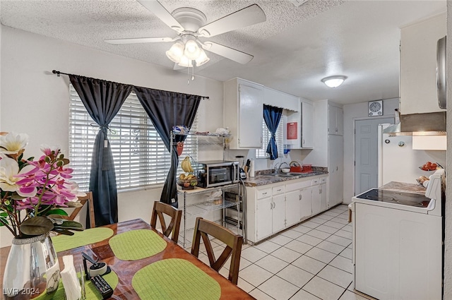 kitchen with light tile patterned flooring, white cabinetry, a wealth of natural light, and electric stove