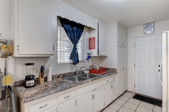 kitchen with white refrigerator with ice dispenser, sink, light tile patterned floors, and white cabinets