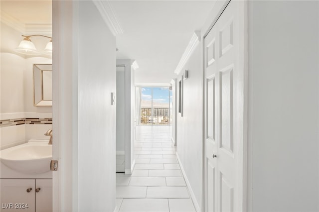 hall with crown molding, sink, and light tile patterned floors