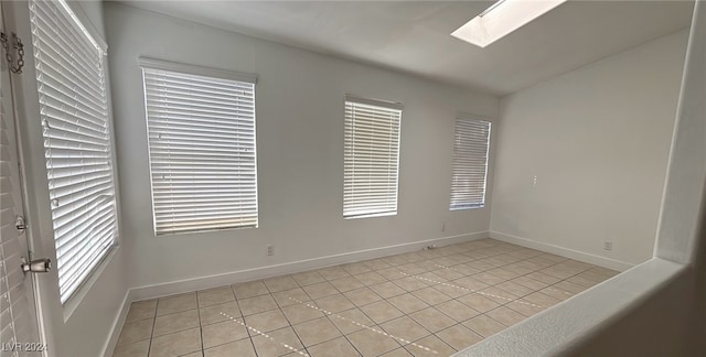 unfurnished room featuring a skylight, light tile patterned flooring, and a wealth of natural light