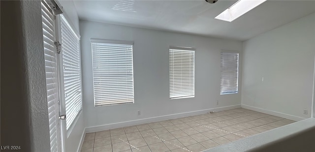 spare room featuring light tile patterned flooring, a skylight, and a wealth of natural light