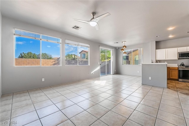 interior space with ceiling fan, white cabinets, appliances with stainless steel finishes, and light tile patterned floors