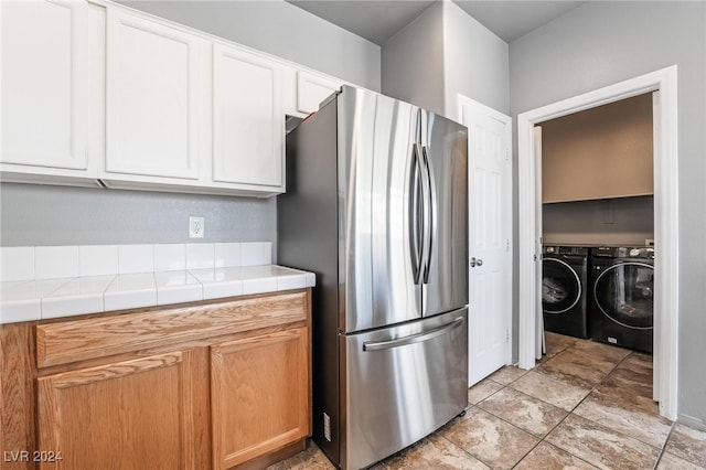 kitchen featuring white cabinets, stainless steel fridge, tile counters, and washing machine and dryer