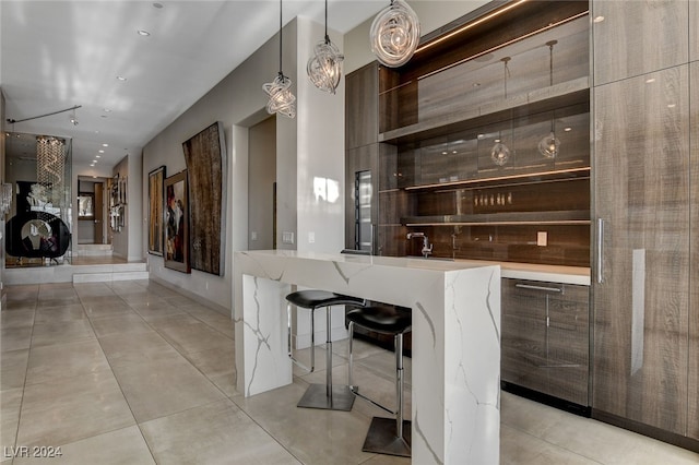 bar with light stone countertops, hanging light fixtures, and light tile patterned floors