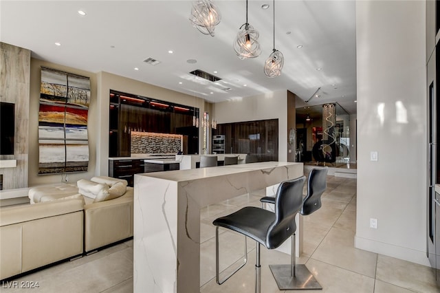 kitchen featuring a kitchen breakfast bar, hanging light fixtures, light tile patterned floors, and tasteful backsplash