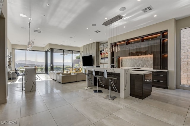 interior space with tasteful backsplash, a mountain view, hanging light fixtures, dark brown cabinets, and light tile patterned floors