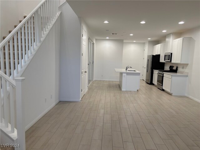 kitchen featuring white cabinetry, sink, a kitchen breakfast bar, a kitchen island with sink, and appliances with stainless steel finishes