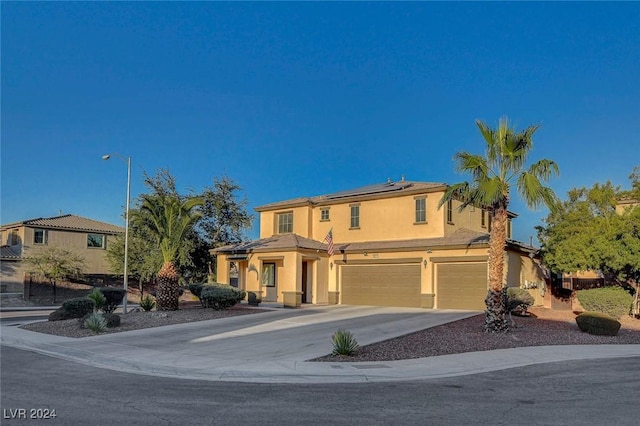 traditional-style house featuring solar panels, driveway, stucco siding, and an attached garage