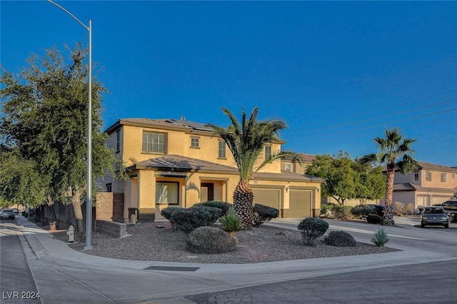 view of front of home featuring roof mounted solar panels, stucco siding, driveway, and a garage