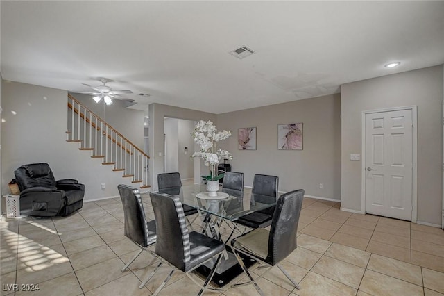 dining room with light tile patterned floors, visible vents, baseboards, stairway, and ceiling fan