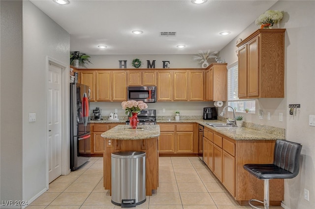 kitchen featuring a center island, sink, light stone countertops, appliances with stainless steel finishes, and light tile patterned floors