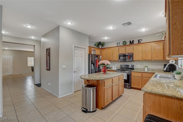 kitchen featuring a kitchen island, sink, light stone counters, stainless steel appliances, and light tile patterned floors