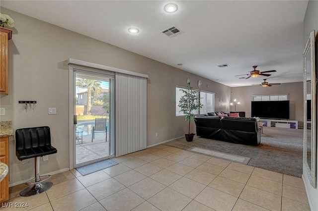 living area with ceiling fan, a wealth of natural light, light tile patterned floors, and visible vents