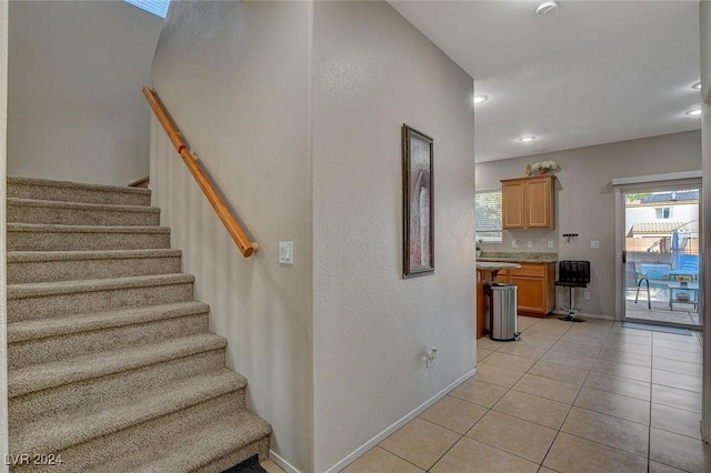stairway featuring tile patterned flooring, baseboards, and recessed lighting
