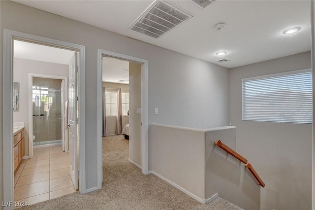 hallway featuring light colored carpet, visible vents, an upstairs landing, and baseboards